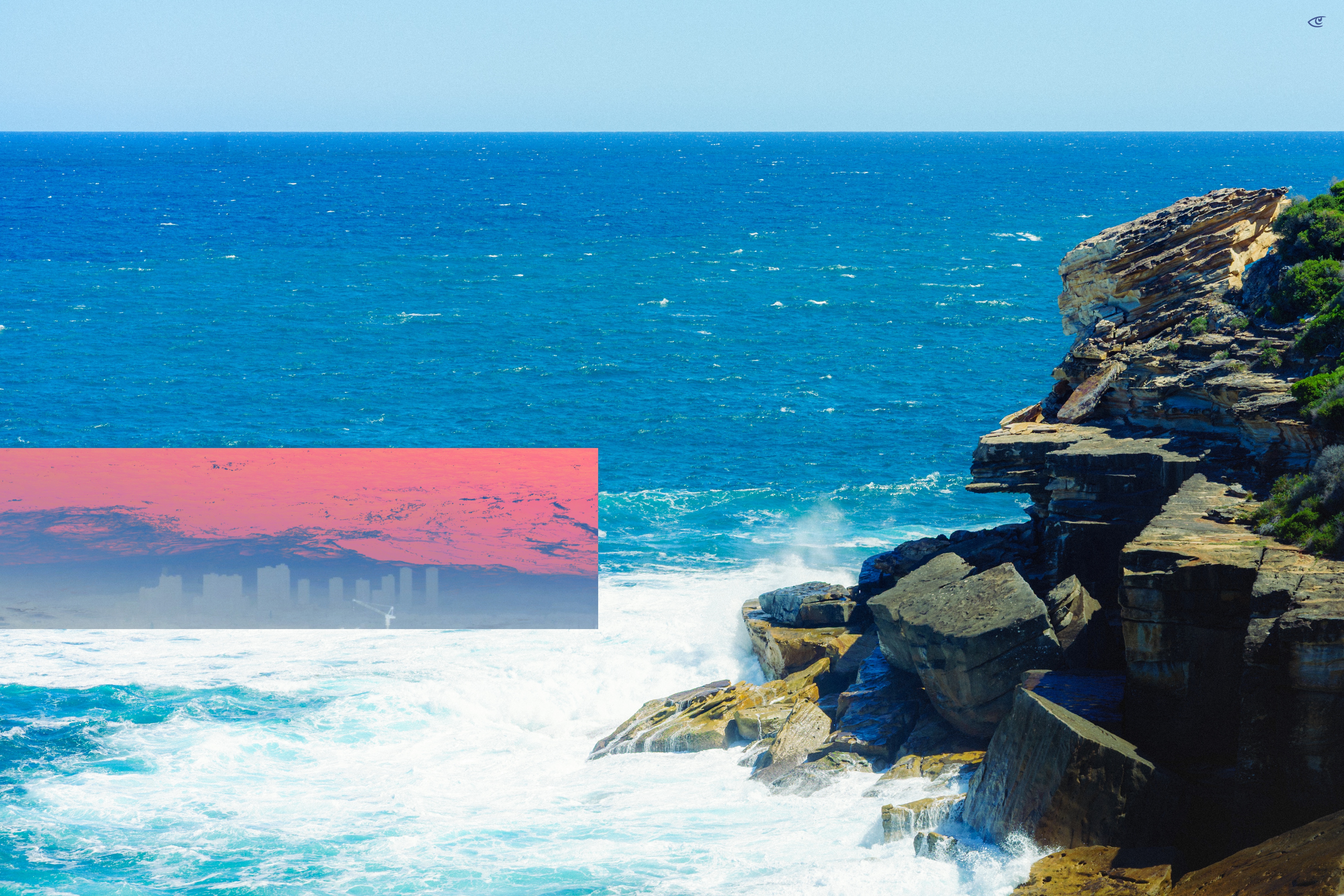 Rocky coastal cliff on the right with waves crashing below, deep blue ocean and clear sky; a semi-transparent pink rectangular overlay on the left shows a faint city skyline silhouette.