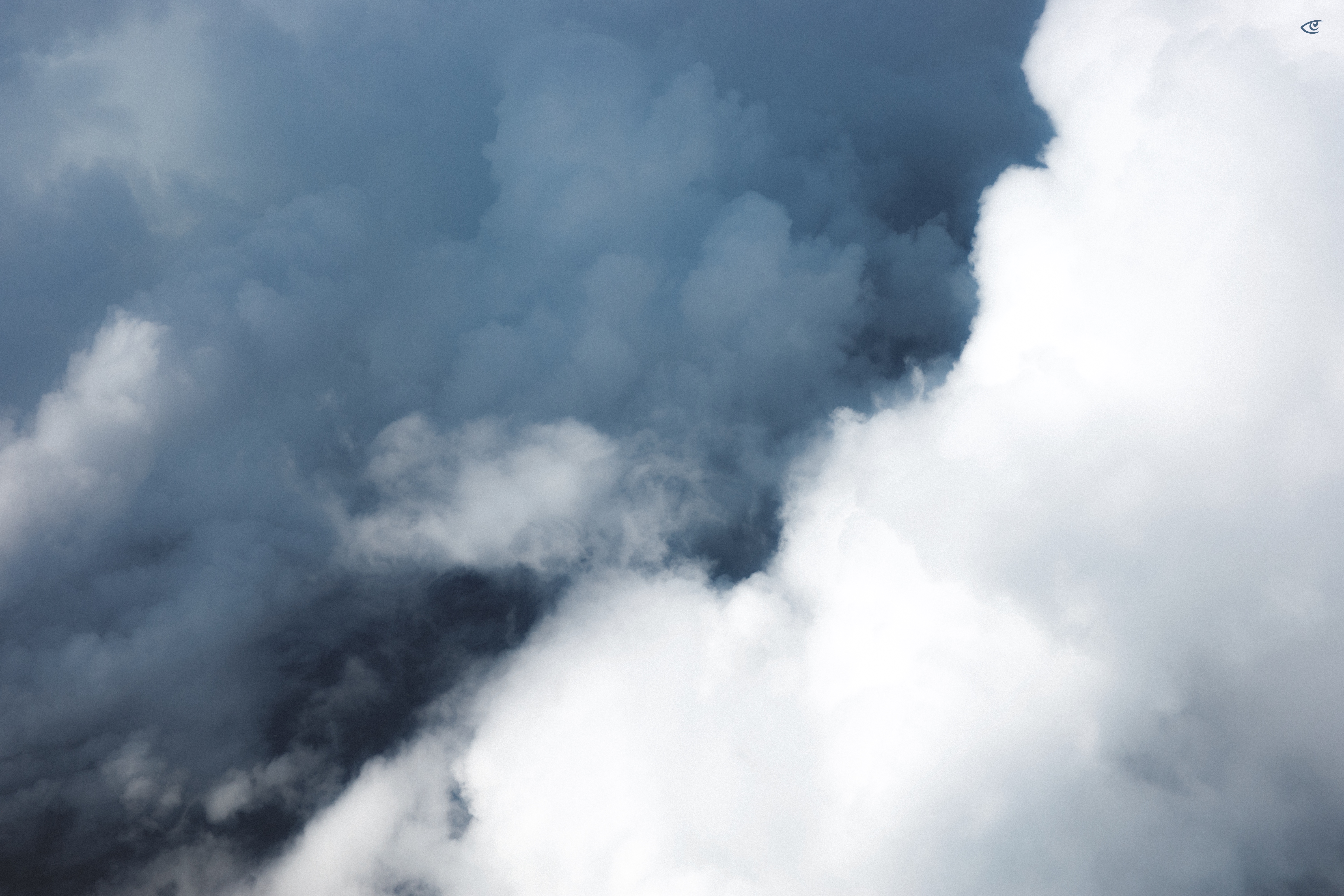 Close-up view of layered clouds, with dense white clouds on the right and darker gray clouds on the left and upper areas, filling the entire frame.