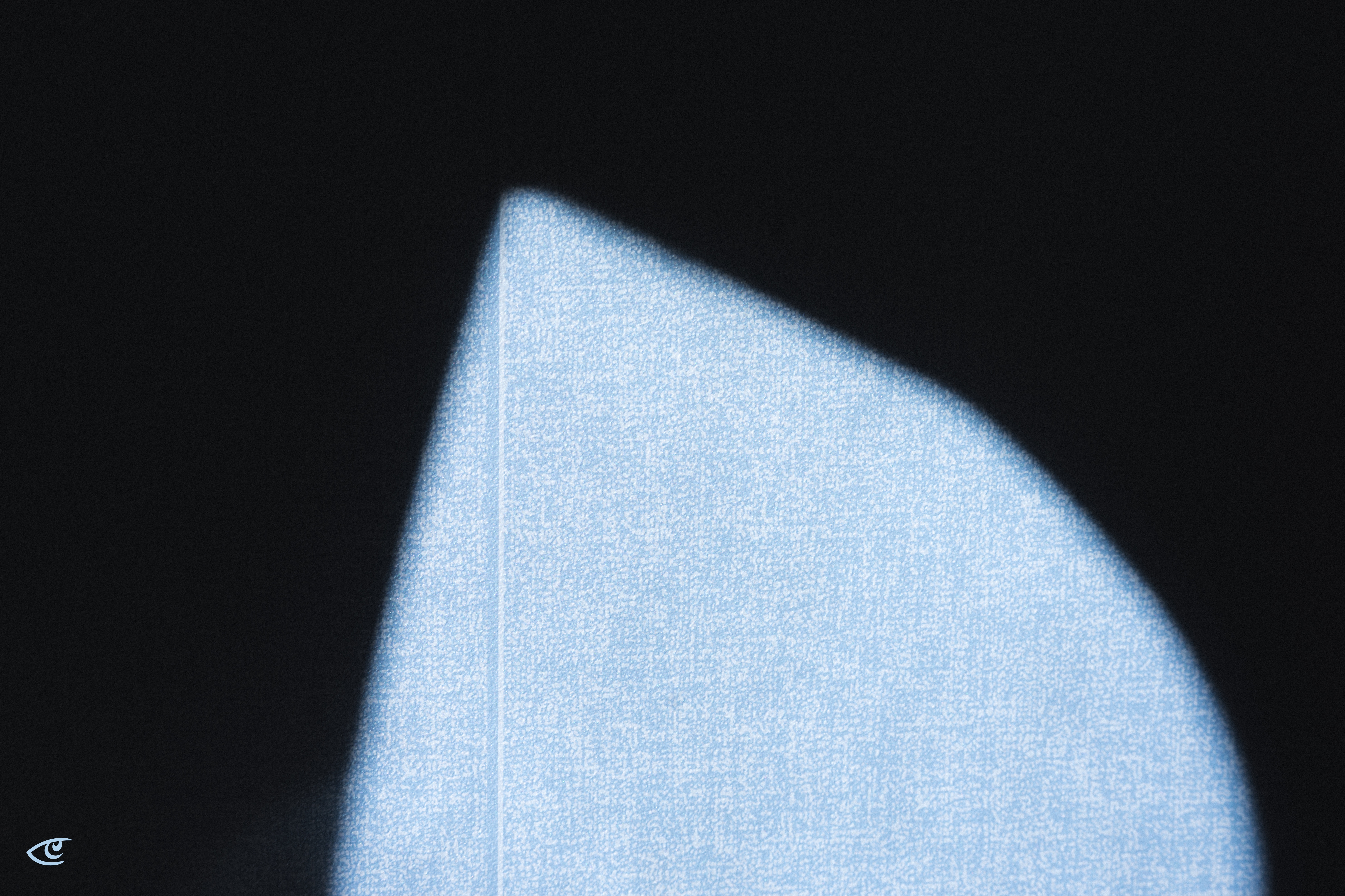 Close-up of a light blue, textured curved shape with a sharp corner, outlined by a thin lighter edge against a dark blurred background.